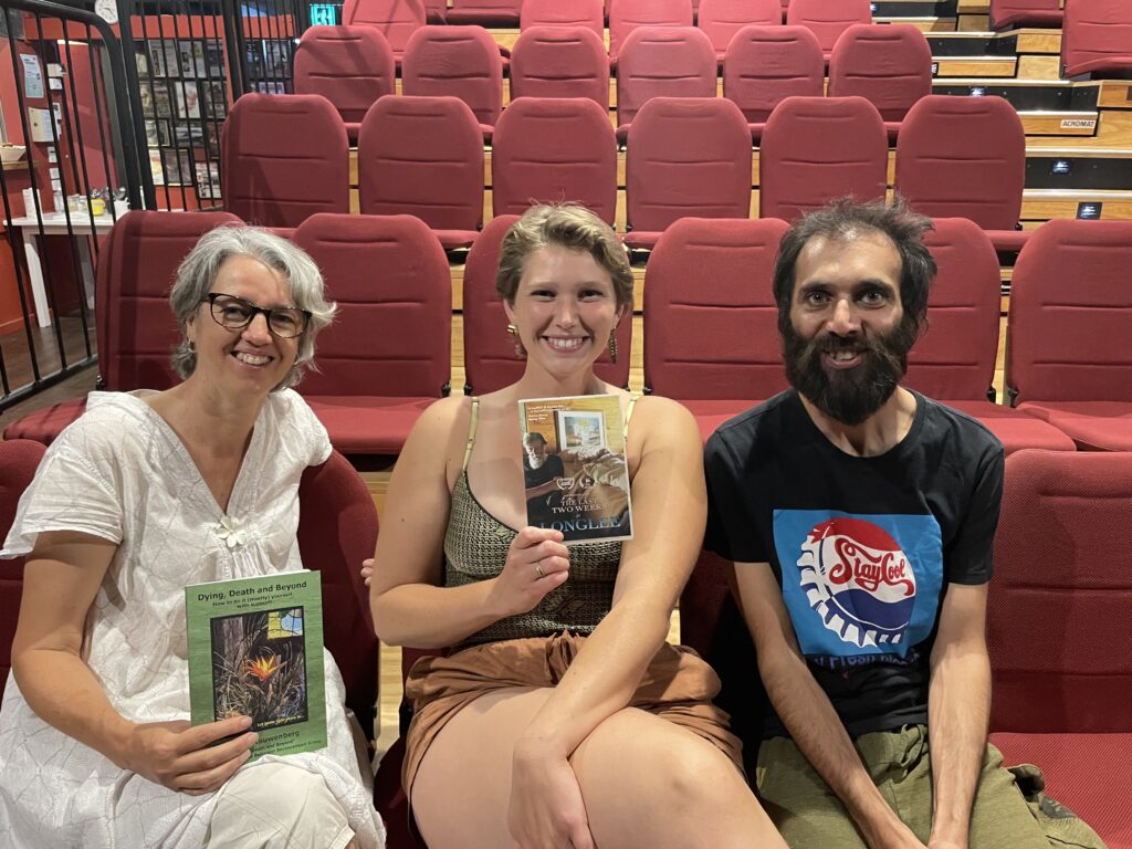 susie, manika and Jagged holding a book and a DVD in a theatre